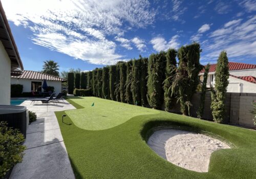 A backyard with a putting green and a small hole.