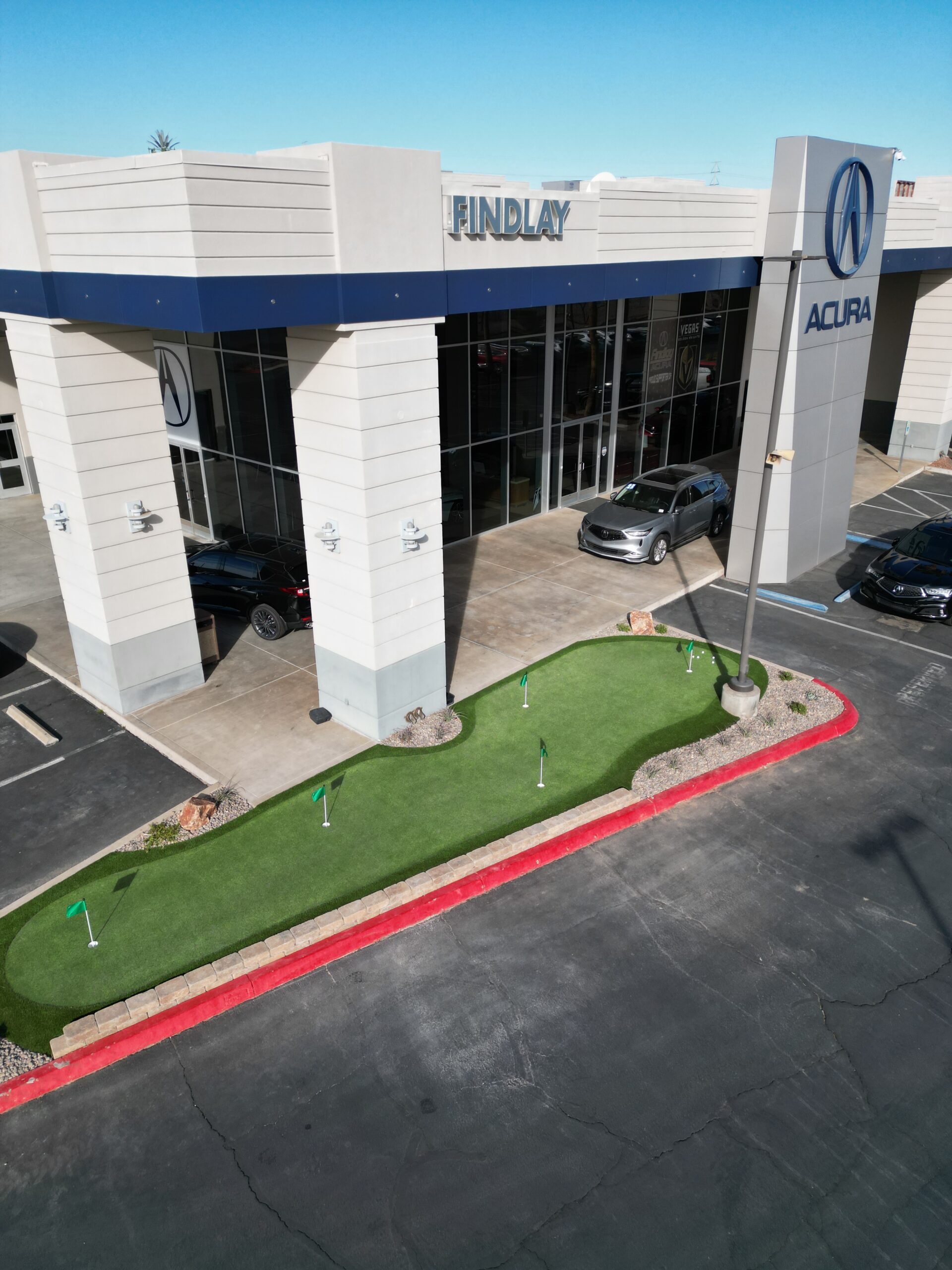 A car dealership with a putting green in the middle of it.